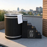 Swedish Cold Nordic Tub Eisbad – auf einer Dachterrasse vor Stadtkulisse, mit Handtuch und dampfendem Wasser