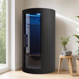 Swedish Cold Sanctuary Solo Infrarotsauna in Schwarz in einem hellen Wohnraum mit Pflanze und Hocker