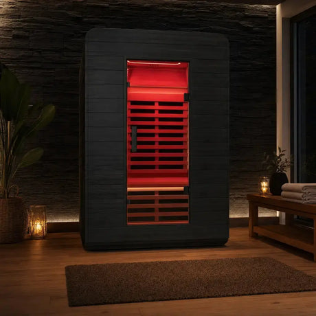 Swedish Cold Ultimate Lux Infrarotsauna in einem dunklen Wohnraum mit Pflanzen und Kerzen, rot beleuchtet