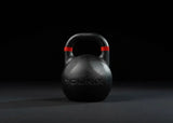 Younix Competition Kettlebell 16 kg Gusseisen, Frontansicht der Variante 12 kg in Schwarz vor dunklem Hintergrund