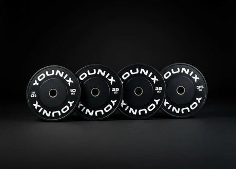 Younix Premium Bumper Plate 20 kg Hantelscheibe, vier schwarze Scheiben stehend vor dunklem Hintergrund